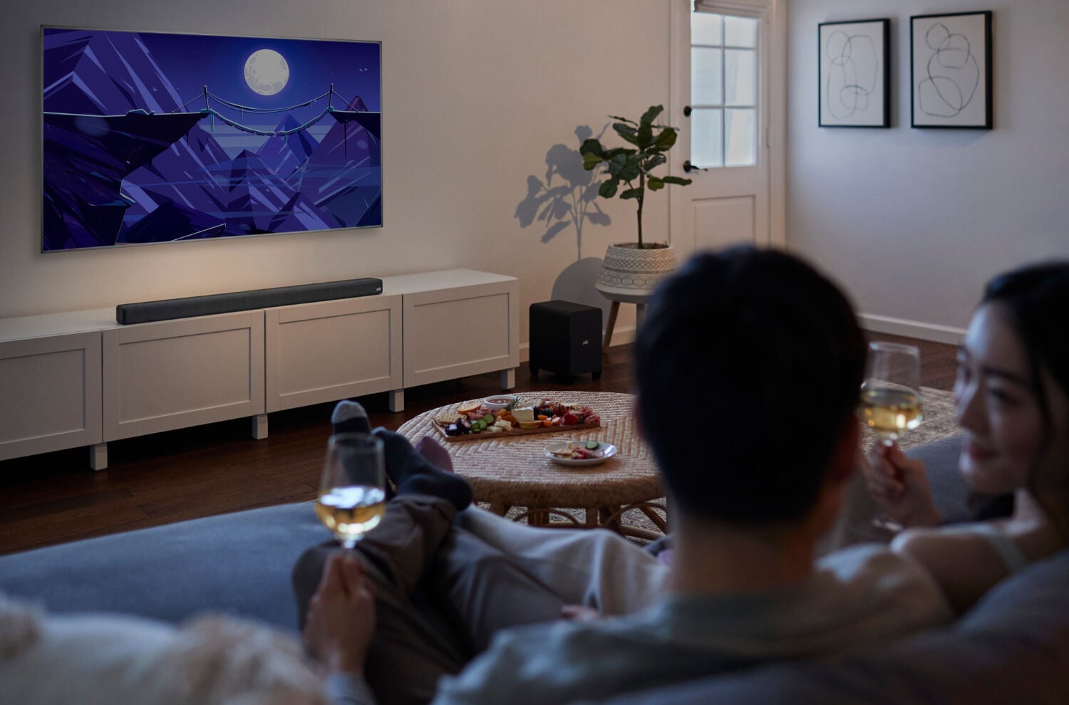 A couple watching TV and drinking wine.