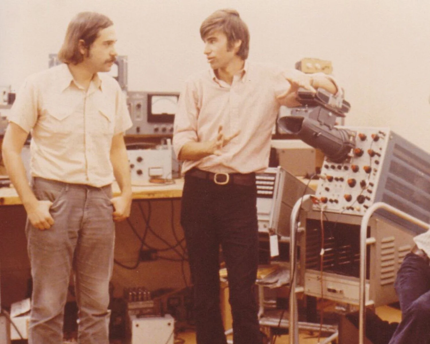 Two men speaking in front of audio equipment